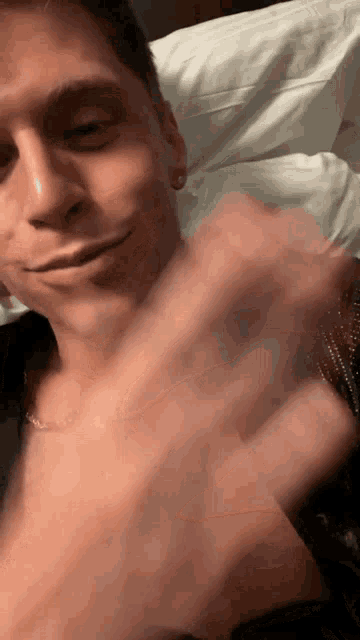 a close up of a man laying on a bed with his hand on his chest