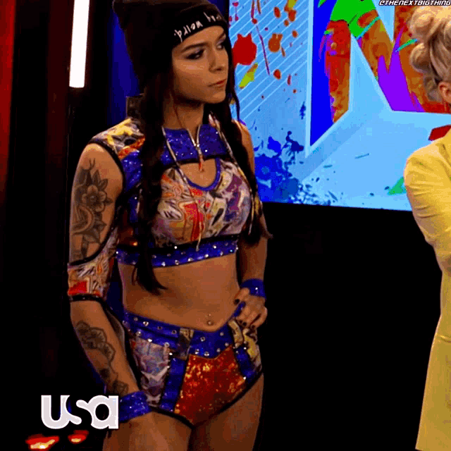 a woman in a wrestling outfit is standing in front of a usa sign