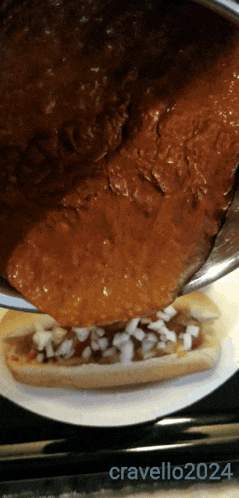 a picture of a chili dog being poured on a plate with the year 2024
