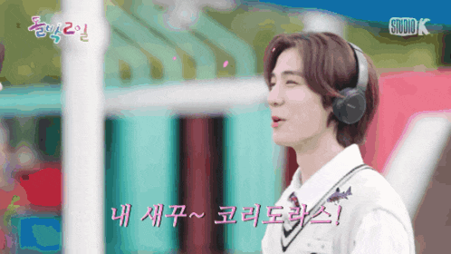 a man wearing headphones is standing in front of a studio k sign