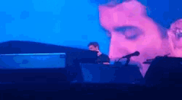 a man playing a keyboard in front of a large screen that says ' yamaha ' on it