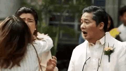 a man in a white shirt is standing next to a woman and talking to her .