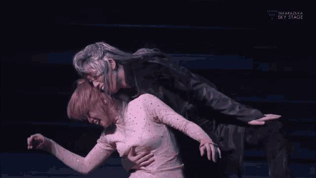 a man and a woman are dancing on a stage that says takarazuka sky stage on it