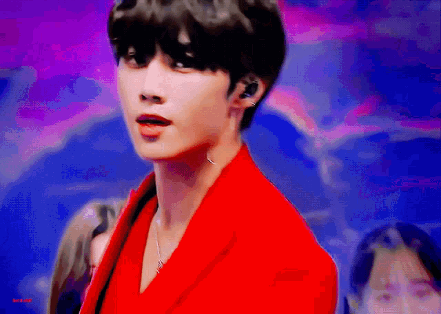 a man in a red jacket is standing in front of a purple and blue background