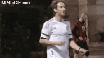 a man in a white adidas shirt is running with a man in a red shirt behind him .