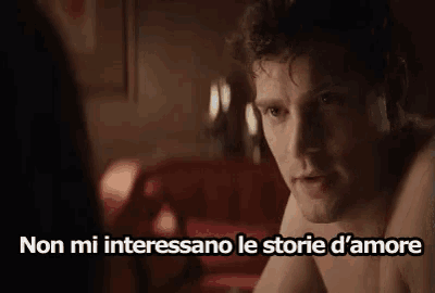 a man without a shirt is looking at a woman in a room .