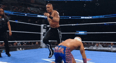 a wrestler is jumping over another wrestler in a wrestling ring with a smack logo in the background