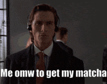 a man in a suit and tie with headphones says me omw to get my matcha