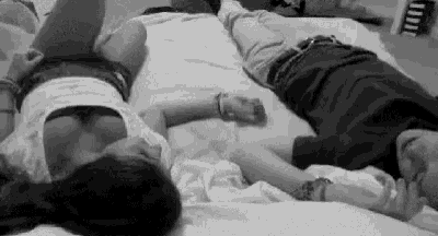 a man and a woman are laying on a bed with their arms around each other .