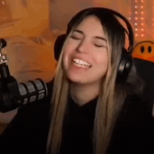a woman wearing headphones and smiling in front of a microphone .