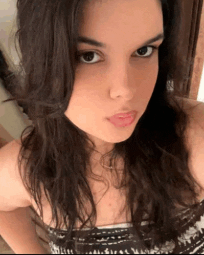 a young woman with long dark hair is taking a selfie with her phone .