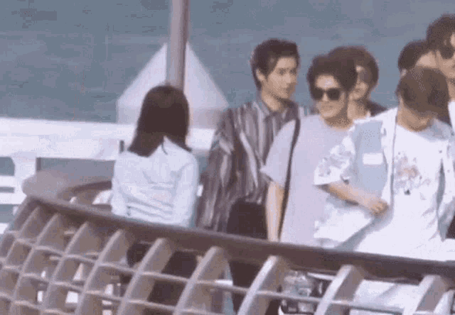 a group of people standing on top of a bridge .