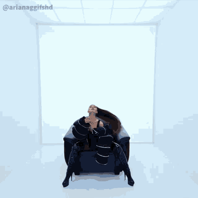 ariana grande is sitting in a chair in a room with a white wall