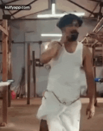 a man in a white tank top and white shorts is walking in a room .