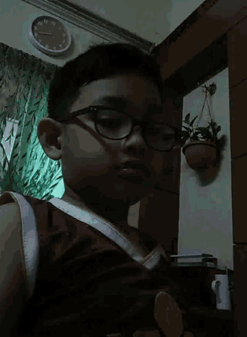 a young boy wearing glasses and a red shirt looks at the camera