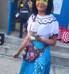 a girl wearing glasses and a blue skirt is holding a cup of coffee