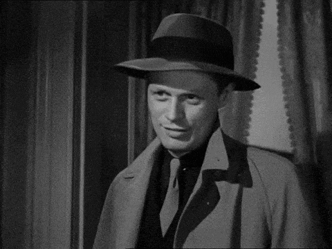 a black and white photo of a man wearing a hat and smiling .