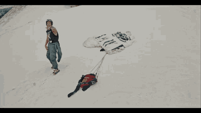 a person standing on top of a snow covered hill with a parachute attached
