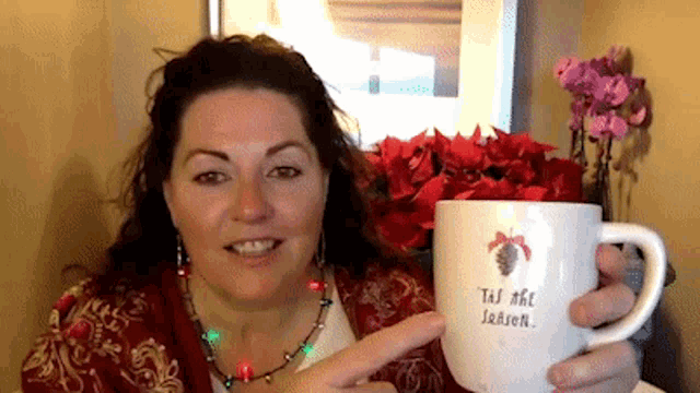 a woman is holding a coffee mug that says " tis the season "