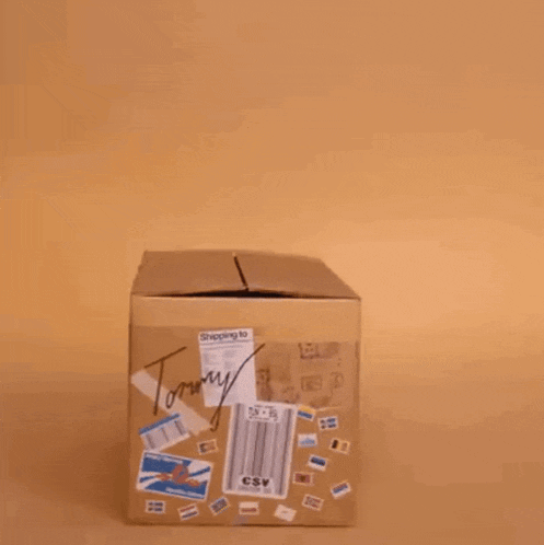 a man in a suit sits in a cardboard box that says tommy on it