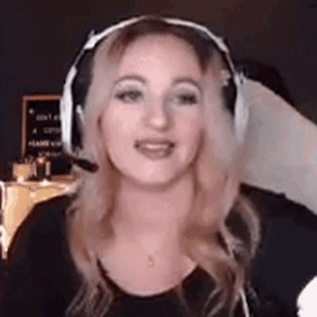 a woman wearing headphones and a microphone is looking at the camera and smiling .