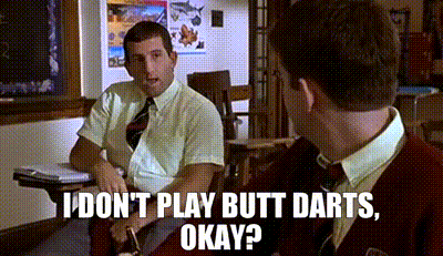 two men are sitting at desks in a classroom and one of them is talking to the other .