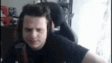 a man wearing headphones and a black shirt is sitting in a chair .