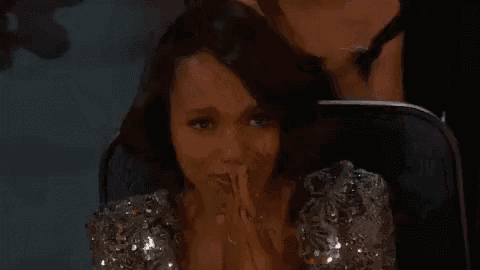a woman is crying while sitting in a chair with her hands folded .