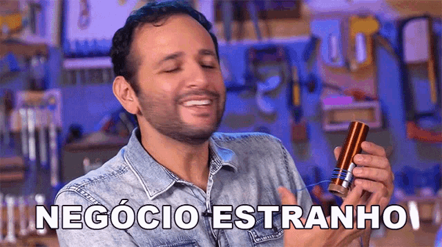 a man in a denim shirt is smiling and holding a piece of metal with the words negocio estranho written on it