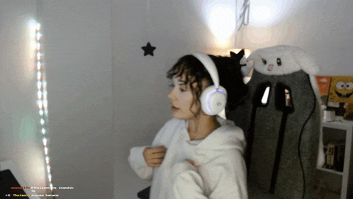 a woman wearing headphones stands in front of a stuffed animal