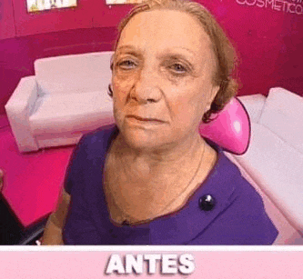 an elderly woman in a purple shirt is sitting in front of a pink couch in a living room .