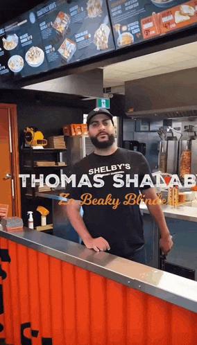 a man wearing a shirt that says shelby 's shawarma on it