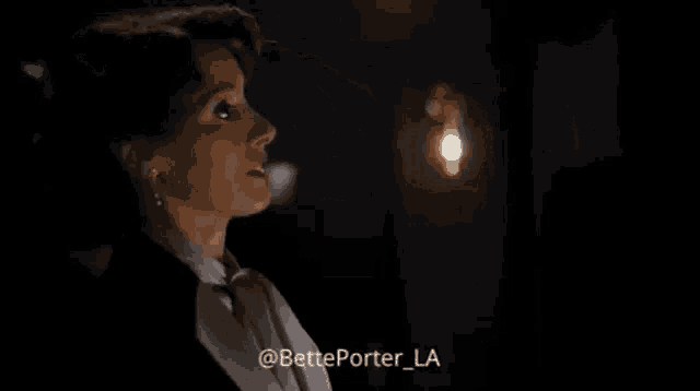 a woman is sitting in a dark room looking down at something .