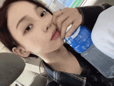 a woman is drinking from a blue bottle that says ' aquafina ' on the label