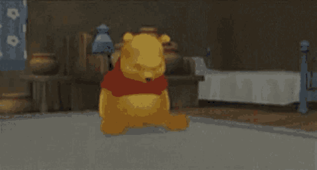 a winnie the pooh teddy bear is sitting on the floor in a room .