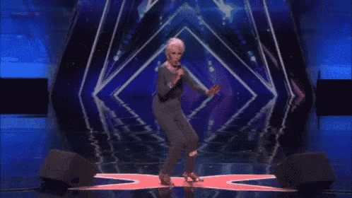 a woman singing into a microphone while dancing on a stage