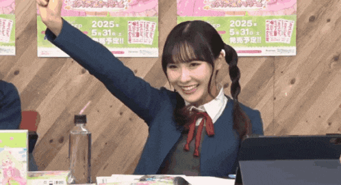 a girl sitting at a table with her fist in the air in front of a poster that says 2025