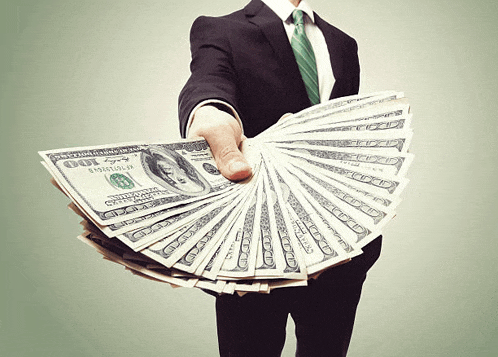 a man in a suit and tie holds a fan of 100 dollar bills in his hand