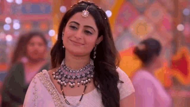 a woman is wearing a necklace and earrings and smiling .