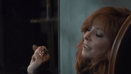 a woman with red hair is wearing a ring on her left hand