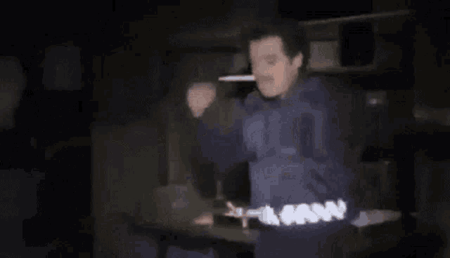 a man in a blue shirt is standing in the dark .