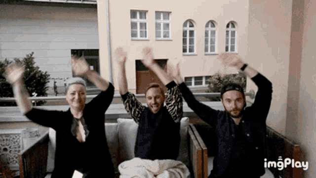 a group of people are sitting on a couch with their arms in the air and the word imgplay is visible in the corner