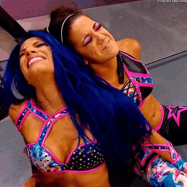 a woman with blue hair is laying on another woman 's chest