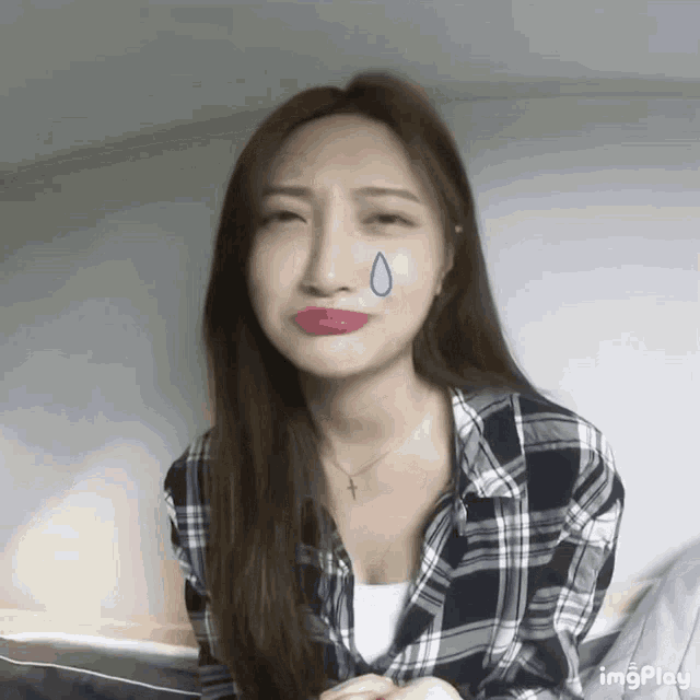 a woman in a plaid shirt has a blue tear coming out of her nose