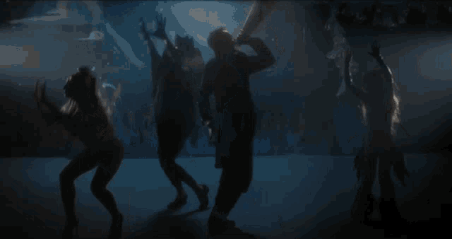 a group of people are dancing in the dark