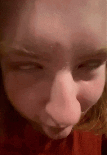 a close up of a person 's face with their eyes closed and a red shirt on .