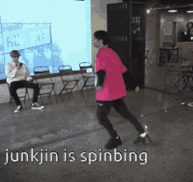 a man in a pink shirt is spinning in a room with other people