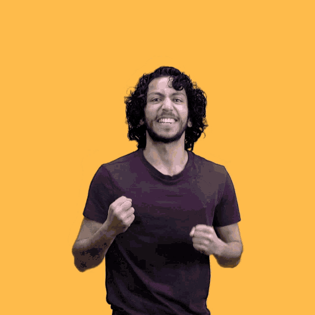 a man with curly hair and a purple shirt is raising his arms in the air