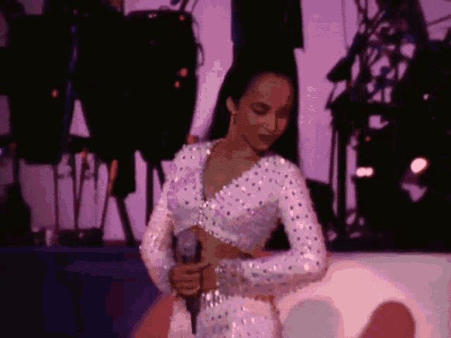 a woman in a crop top is singing into a microphone on a stage
