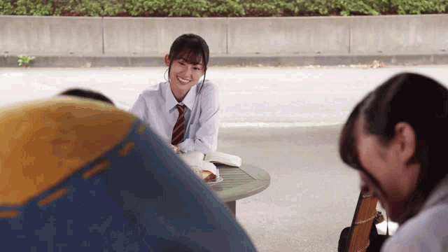 a girl in a tie is sitting at a table with other girls